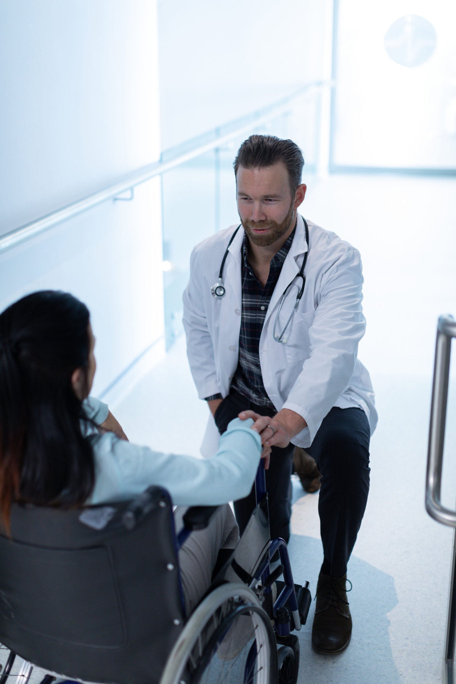 High angle view of Caucasian male doctor consoling female patient in the corridor at hospital